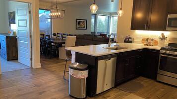 A modern kitchen with a central island, stainless steel appliances, and pendant lighting.