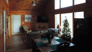 A cozy cabin interior with a dining area, a sofa, a ceiling fan, and a Christmas tree. - Cozy & Comfy with all the Views  (Gatlinburg)