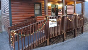 A log cabin with a porch decorated with lights and a sign reading "BEARADISE". - Cozy & Comfy with all the Views  (Gatlinburg)