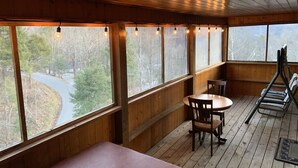 A wooden cabin with a dining area, a bench, and a view of a winding road through trees. - Cozy & Comfy with all the Views  (Gatlinburg)