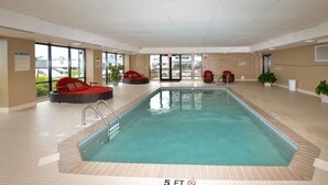 An indoor swimming pool with a 5 ft depth marker, red seating areas, and a tiled floor. - Grand Victorian on the Beach, Summer (Old Orchard Beach)