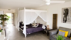 A bedroom with a four-poster bed, a grey sofa, a small table, and a potted plant. - ✨A piece of Heaven✨Ocean view, Orient Bay beach & Saint Barthelemy (Saint Martin)