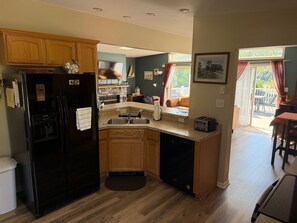 Una cocina con armarios de madera, un refrigerador negro, un lavavajillas integrado y una ventana con vistas a una terraza.