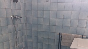A bathroom with blue tiles, a shower, a toilet, and a sink. - APARTMENT LA DAME DE FER (GOSIER)
