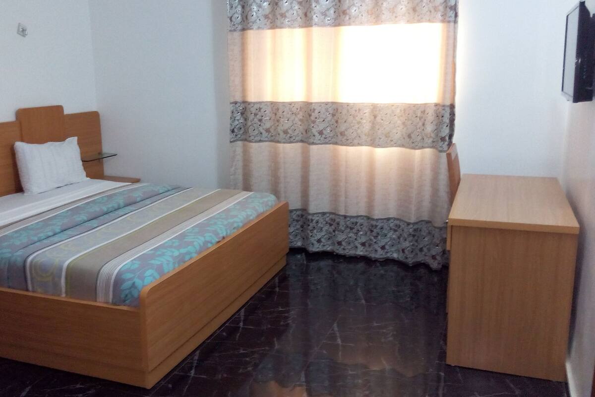 A bedroom with a wooden bed, a bedside table, and a small wooden cabinet.
