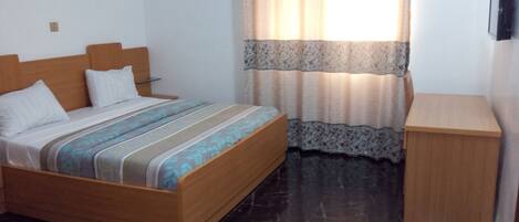 A bedroom with a wooden bed, a bedside table, and a small wooden cabinet.