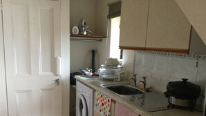A compact kitchen with a washing machine, a sink, and a stove.