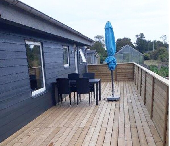Enjoy a tranquil outdoor space with a table, chairs, and umbrella, surrounded by lush gardens.