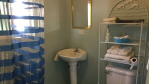 Une salle de bain avec un lavabo sur colonne, des toilettes et un porte-serviettes avec des serviettes pliées.