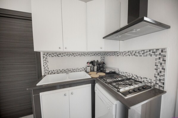 A modern kitchen with white cabinets, a stainless steel stove, and a tiled backsplash.