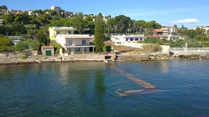 A coastal town with buildings near the water, a pier, and a rocky shoreline. - Villa Francesca Sicily 8, Apartment in Villa on the sea (casteldaccia)