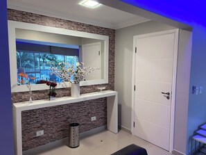 Un intérieur moderne avec un mur en pierre, une console blanche, un miroir et une porte.