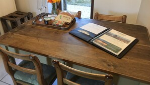 Una mesa de madera con un menú, un tarro de mermelada, una hogaza de pan y un florero con flores.