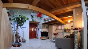 Un'ampia zona giorno con soffitto alto, camino, televisione e una colonna in pietra.