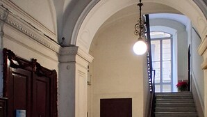 Un corridoio con pavimento a disegno, una scala e una porta con pomello decorativo.