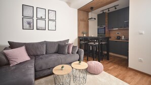 Un salon moderne avec un canapé gris, une table à manger et une cuisine en arrière-plan.