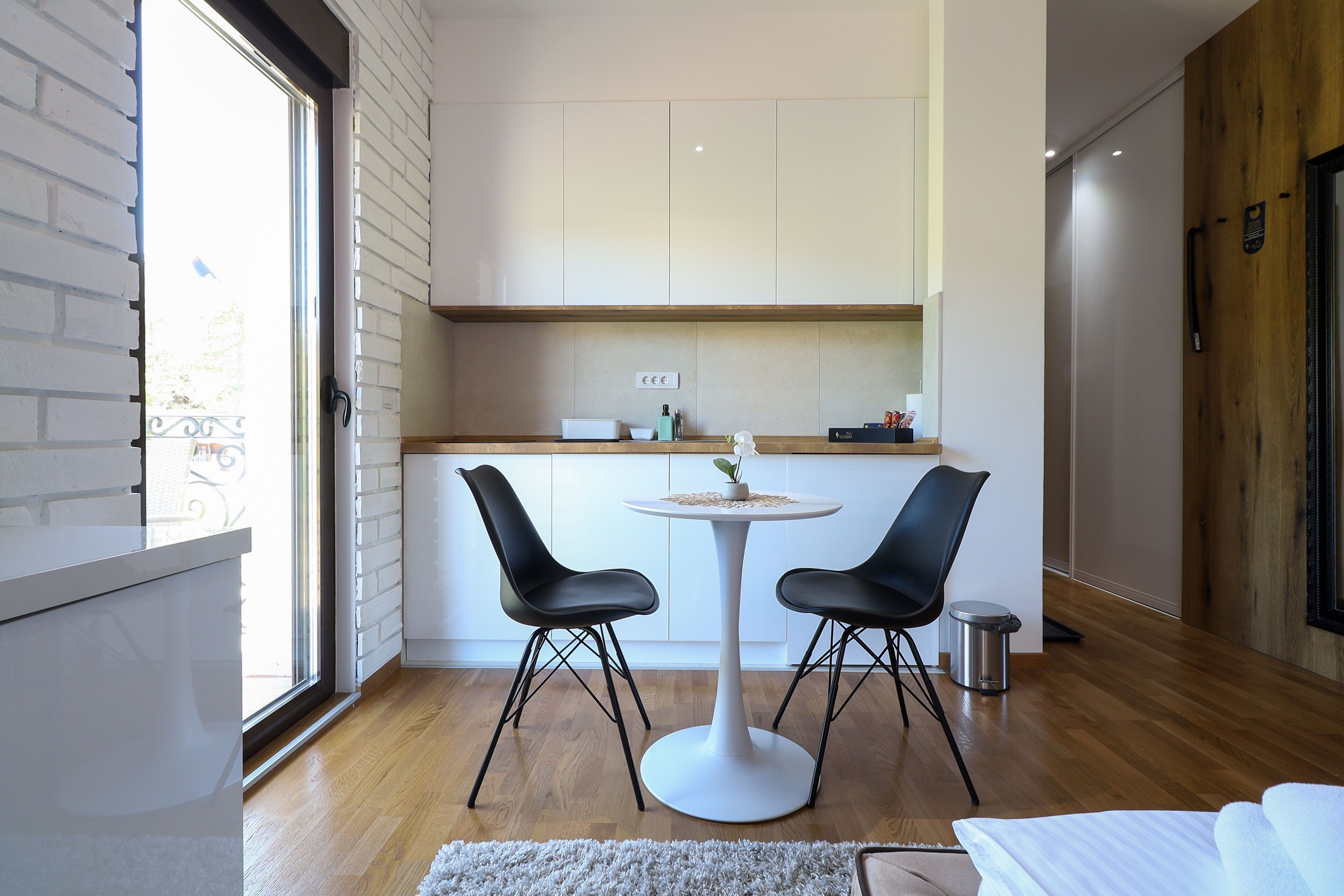 Una cocina moderna con una mesa redonda y dos sillas, una encimera blanca y vistas a través de un ventanal.