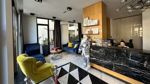 Un hall d’hôtel moderne avec un comptoir d’accueil, un espace salon et de grandes fenêtres.