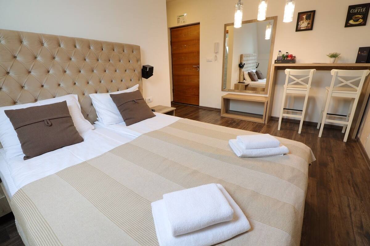 A neatly made bed with a striped bedspread, two pillows, and folded towels.
