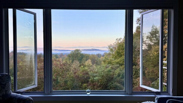 A room with a large window offering a view of a forested landscape and distant mountains. - Mountain-view House ~ Mins To Middlebury, Flex Cancellation Policy (Cornwall)