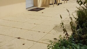 Een gebouw met balkon, een deur en een tafel met stoelen.