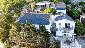 Uma casa moderna com um grande telhado de painéis solares, piscina e varanda com mobiliário de exterior.