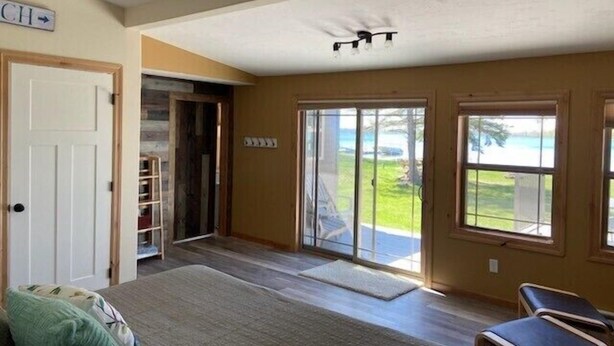 Una habitación amplia con una cama grande, una puerta corrediza de vidrio que da a un balcón y una silla junto a la ventana.