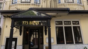 A corner building with a bay window, a fire escape, and a sign reading "775 Bush".