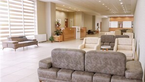 Un hall d’entrée spacieux avec un canapé gris, des fauteuils et un comptoir d’accueil.
