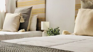 A hotel room with two beds, a headboard with horizontal stripes, and a small bedside table with a lamp and a plant. - Canaryislandshost l Surf Lanzarote (Caleta de Famara)