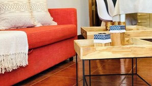 A cozy living area with a red sofa, patterned pillows, and a small wooden table with decorative items. - Canaryislandshost l Surf Lanzarote (Caleta de Famara)