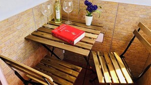 A wooden table with a red book, two wine glasses, a bottle of wine, and a potted plant. - Canaryislandshost l Surf Lanzarote (Caleta de Famara)