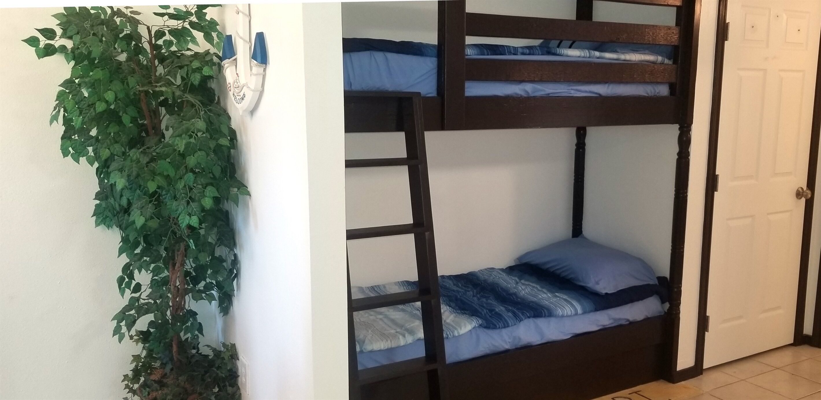 Een stapelbed met twee verhogingen, een bloempot en een witte deur.