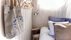 Una habitación con una cama, una mesita de noche con un ordenador portátil y un bolso colgado.
