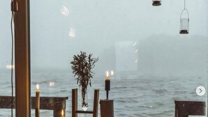 Un rincón exterior acogedor con una computadora portátil, velas y vistas al mar.