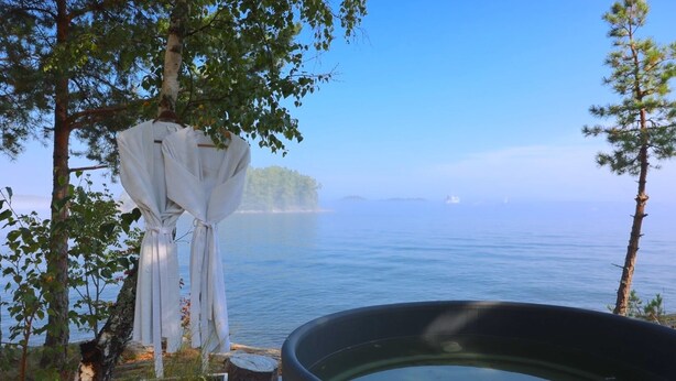 Un entorno tranquilo junto al lago, con un jacuzzi, un pabellón blanco y una terraza de madera.