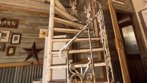 Ein rustikales Interieur mit einer Wendeltreppe, Holzbalken und einer Sternverzierung an der Wand.