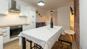 A compact kitchen with modern appliances, a dining table, and a small seating area. - Deluxe Apartment near Bridge (Zadar)