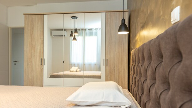 A bedroom with a bed, a wardrobe, and a mirror. - Deluxe Apartment near Bridge (Zadar)