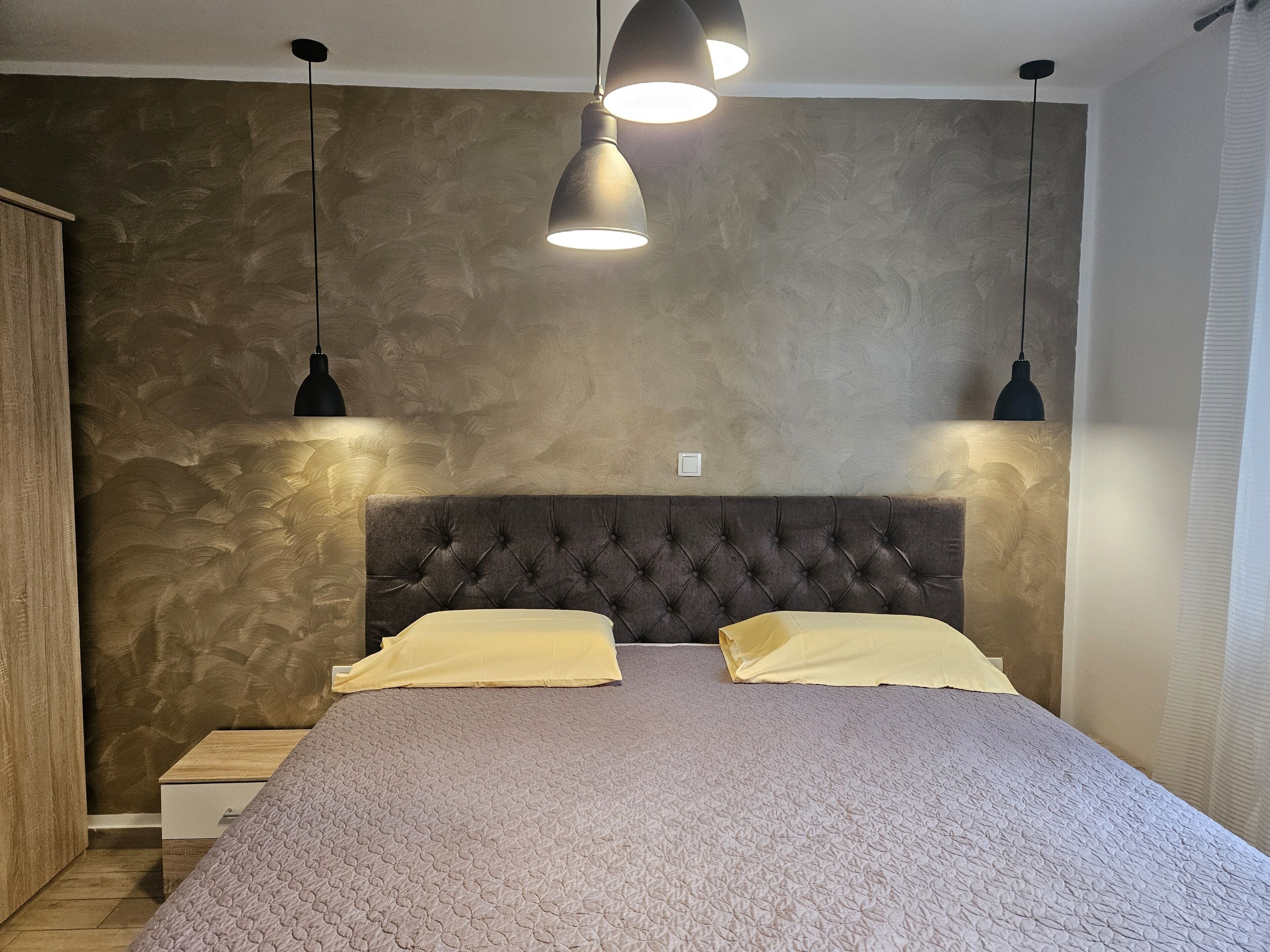 A bedroom with a tufted headboard, a wooden nightstand, and two bedside tables.
