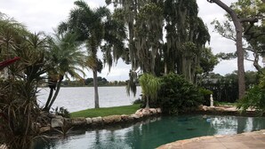 Una piscina rodeada de vegetación tropical y vista a un lago.