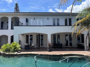 Ein zweistöckiges Gebäude mit Schwimmbad, Außenbereich zum Sitzen und einer überdachten Terrasse.