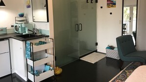 Una cocina moderna con un lavamanos, un tostador y un box de ducha de vidrio.