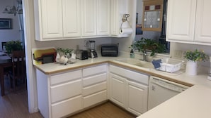Una cocina con armarios blancos, un tostador, una licuadora y un lavamanos.