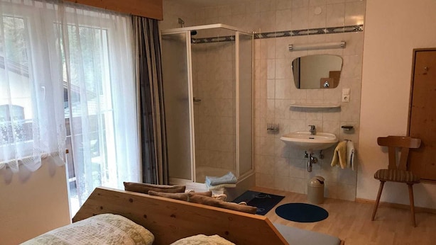 Ein Schlafzimmer mit zwei Betten, einer Dusche, einem Waschbecken und einem Spiegel.
