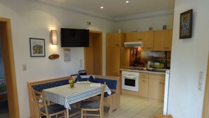 A compact kitchen with wooden cabinets, a built-in oven, and a dining area with a table and chairs. - Cozy 3-star vacation home, quiet and close to nature for 4 people / 2 bedrooms (Zwiesel)
