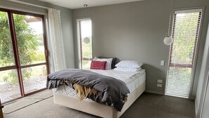 A bedroom with a large bed, a sliding glass door to the outside, and a ceiling light.