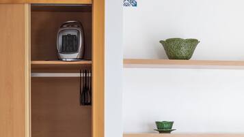 Un dormitorio con un armario de madera, una cama con ropa de cama blanca y un tazón verde sobre una estantería.