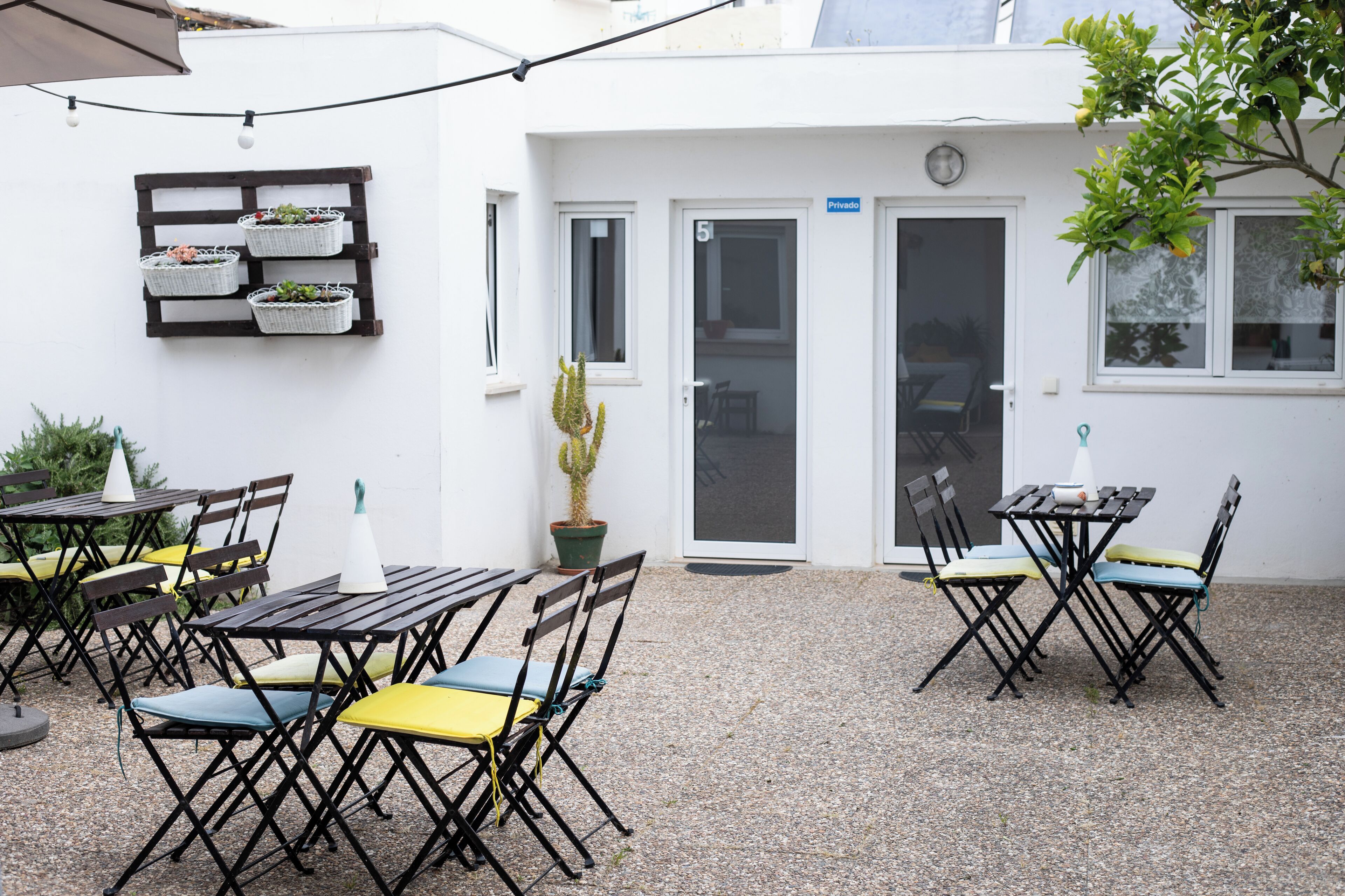 Un patio con mobiliario exterior, un cactus y una puerta con la inscripción 'Privado'.