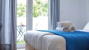 Un dormitorio con cama, ventana y vistas al verdor exterior.